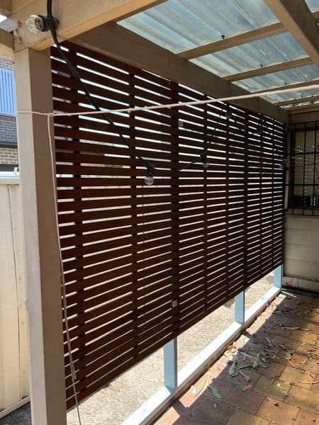 Dark hardwood slat privacy screen fixed between pergola posts in Mascot